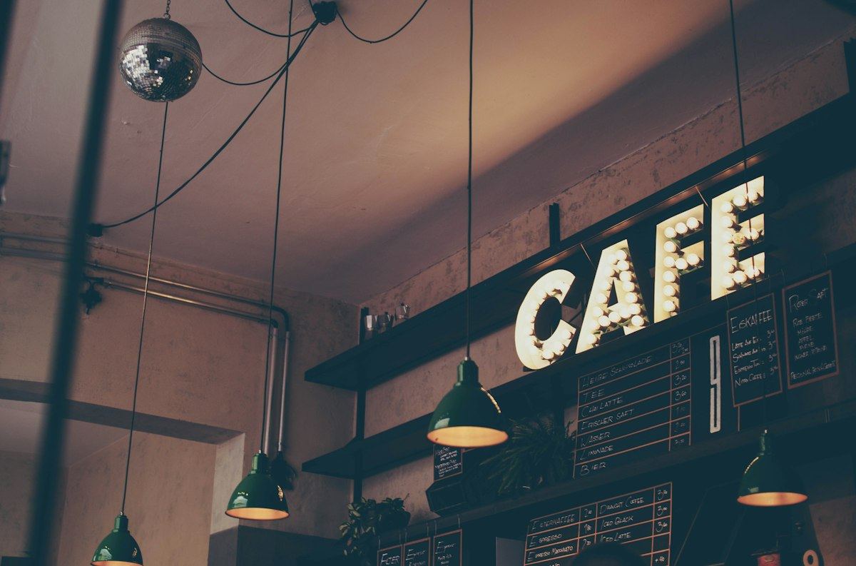 Warm café interior with a glowing CAFE sign