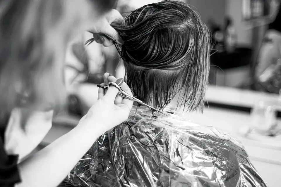 Black and white photo of a stylist cutting a client's wet hair